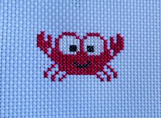 a close up of a red crab on a blue background with white stitching in the middle