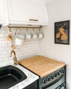 a kitchen with a sink, stove and wooden cutting board on the wall above it