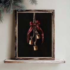 a painting with bells hanging from it's side on a shelf next to a christmas tree