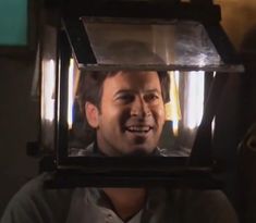 a man is smiling in front of a light fixture with his mouth open and tongue out