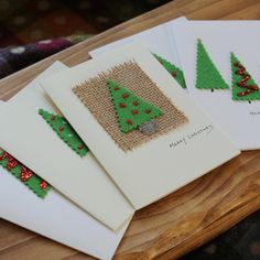 four cards with christmas trees on them are sitting on a wooden table next to each other