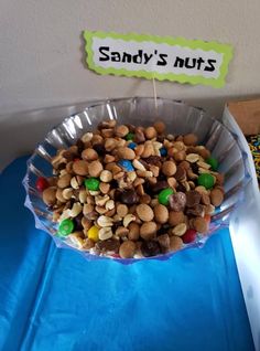 a bowl filled with nuts and candy on top of a blue tablecloth covered table