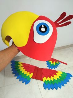 a hand is holding up a paper bird that looks like it has blue eyes and yellow beak