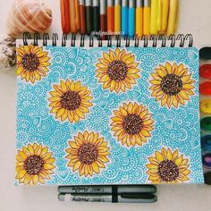 a notebook with sunflowers on it next to crayons and markers