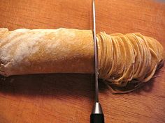 a piece of bread sitting on top of a wooden cutting board next to a knife