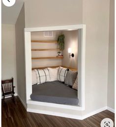 a bed in the corner of a room that is painted white and has pillows on it