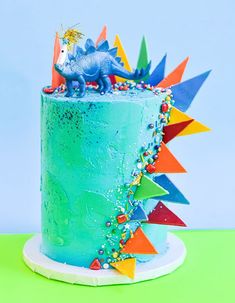 a blue cake with sprinkles and a dragon on top is sitting on a green table