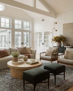 a living room with couches, chairs and a table in front of large windows