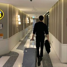 a man is walking down the hallway with his luggage