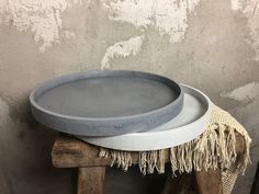 two cement plates sitting on top of a wooden stool