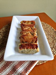 a white plate topped with lasagna rolls on top of a woven place mat