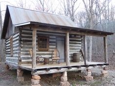 an old log cabin sits in the middle of a forest with two rocking chairs on the porch