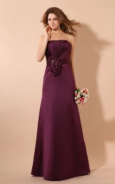 a woman in a long purple dress with flowers on the waist and one hand near her face