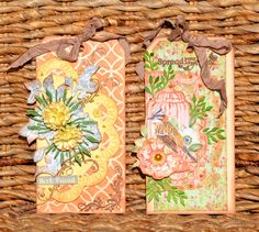 two tags with flowers on them sitting in a wicker basket next to each other