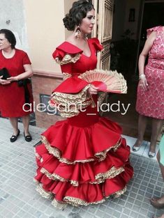 a woman in a red dress is standing outside