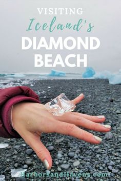 a person's hand with ice on it and the text visiting iceland's diamond beach