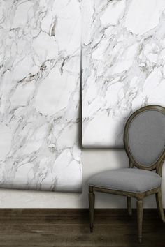 a chair sitting in front of a white marble wall with a mirror on it's side