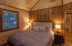 a bed in a bedroom with wooden walls