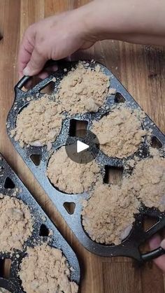 two people are making muffins on a wooden table