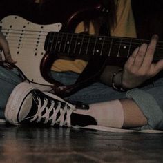 a person sitting on the floor playing an electric guitar