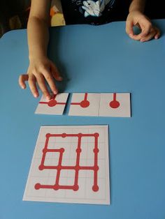 a young child is playing with some red and white squares on a blue table top