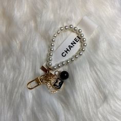 a chanel key chain with charms and beads on top of a white furry surface