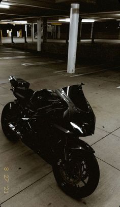 a black motorcycle parked in an empty parking garage with no one on it's bike