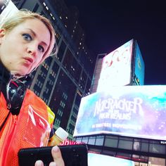 a woman standing in front of a building holding a cell phone