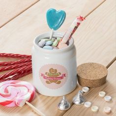 a cup filled with candy and lollipops on top of a wooden table