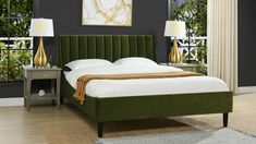 a bed with a green headboard and two lamps on either side of the bed