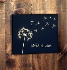 a dandelion with the words make a wish written on it is hanging on a wooden wall