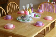 a wooden table topped with lots of pink and purple cake on top of it's plates