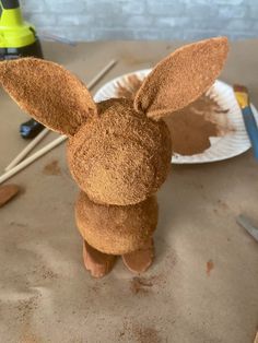 a stuffed animal sitting on top of a table next to a paper plate and paintbrushes