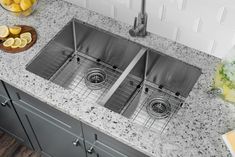 two stainless steel sinks in a kitchen with granite counter tops and gray cabinets, surrounded by lemons