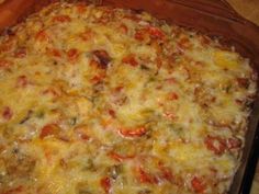 a casserole dish with cheese, tomatoes and meat in it on a wooden table