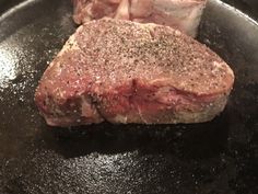 two steaks are cooking in a frying pan on the stove with seasonings