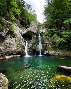 there is a small waterfall in the middle of this river with green water and rocks