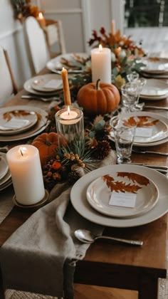 the table is set with plates, candles and napkins for thanksgiving dinner guests to enjoy