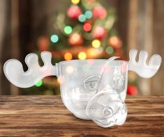 a glass cup with a face on it sitting on top of a wooden table next to a christmas tree