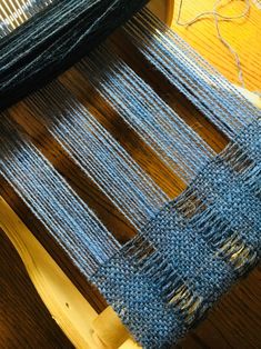 a close up of a weaving machine with yarn on it's sides and a piece of wood in the background