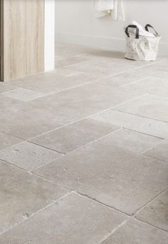 a white bathroom with grey tile flooring next to a sink