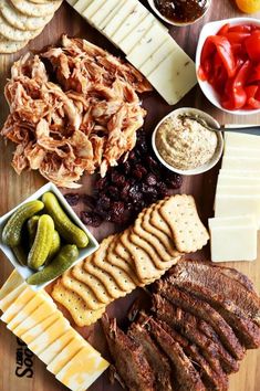 an assortment of cheeses, crackers, pickles and meat on a cutting board