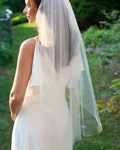 a woman in a white wedding dress looking back at the camera with a veil on her head