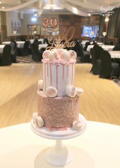 a three tiered cake sitting on top of a table in front of tables with chairs