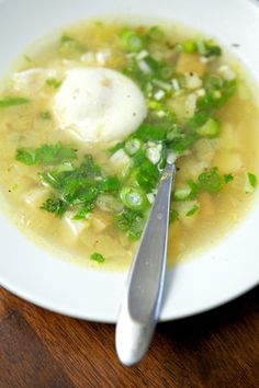 a white plate topped with soup and a spoon