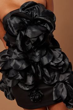 a woman wearing a black dress with ruffles on it