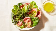 a white plate topped with lettuce and meat next to a glass of green juice