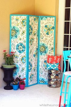 a room divider made out of fabric with flowers on it and potted plants in the corner