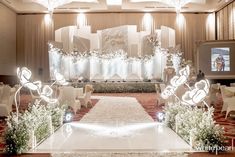 an indoor wedding venue decorated with white flowers and hearts on the aisle, surrounded by chandeliers