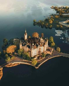 an aerial view of a castle in the middle of water with trees and buildings around it